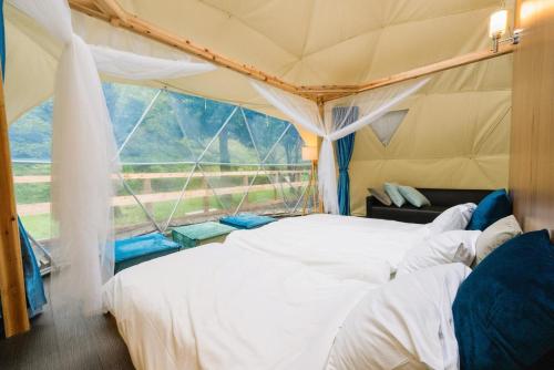 two beds in a tent with a large window at SPRINGS VILLAGE Ashigara Tanzawa Onsen Resort & Gl - Vacation STAY 51635v in Hata