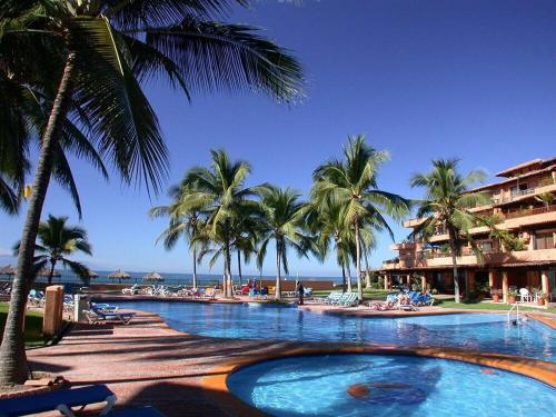 a large swimming pool with palm trees and a resort at studio Opa in Puerto Vallarta