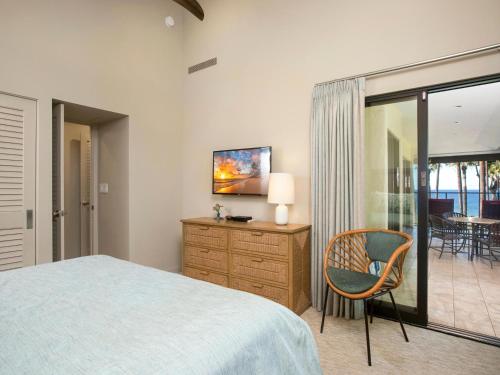 a bedroom with a bed and a chair and a television at Wailea Elua Village 1102 in Wailea
