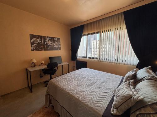 a bedroom with a bed and a desk and a window at ENB Flat Super Decorado p até 4 pp no centro de SBC in São Bernardo do Campo
