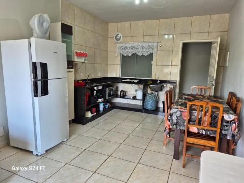 a kitchen with a white refrigerator and a table and chairs at Apartamento na Praia de Enseada in São Francisco do Sul