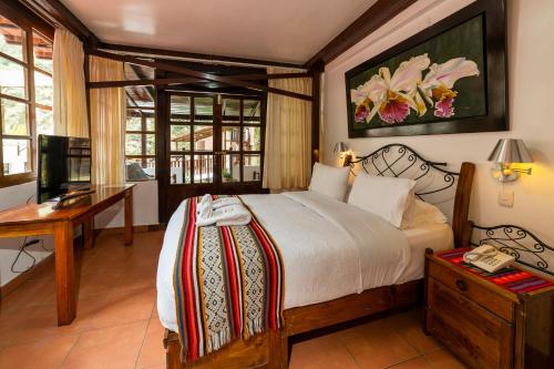 a bedroom with a bed and a desk with a telephone at Gringo Bill's Boutique Hotel in Machu Picchu
