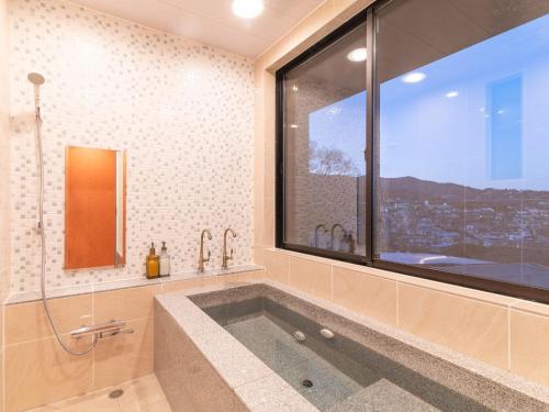 ein Badezimmer mit Badewanne und großem Fenster in der Unterkunft Pension Alhambra - Vacation STAY 15537v in Manazuru