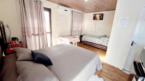 um quarto com uma cama e um sofá em uma sala em KITNET k3 em TORRES-RS - Na mais bela praia Gaúcha - Frigobar - micro-ondas - Banheiro - Ar condicionado split - TV smart - Wi-Fi - Anfitriã SuperHost no BNB em Torres