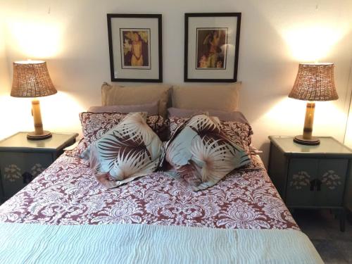 a bed with three pillows on it with two lamps at Kihei Beach Condo, Romantic Kamaole II in Kihei