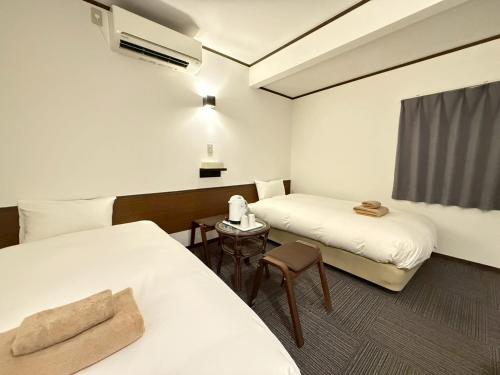 une chambre d'hôtel avec deux lits et une table dans l'établissement Hakodate City - Hotel - Vacation STAY 40640v, à Naka-hamachō