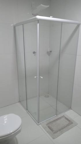 a shower with a glass door next to a toilet at Pousadinha Litoral in Mucuri