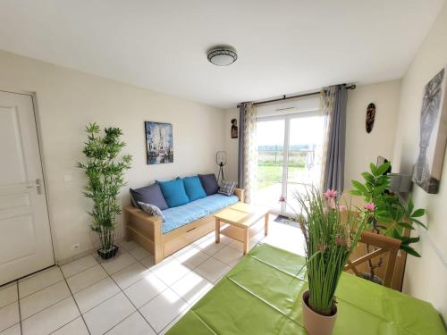 a living room with a blue couch and some plants at Havre de paix à Azay-le-Rideau - piscine chauffée in Azay-le-Rideau