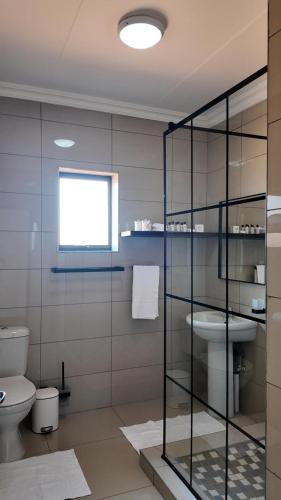 a bathroom with a toilet and a glass wall at The Pebbles-UB in Mahikeng