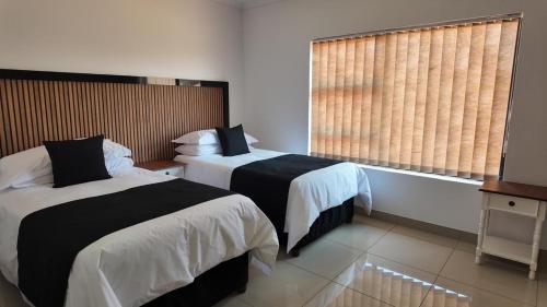a hotel room with two beds and a window at The Pebbles in Mahikeng