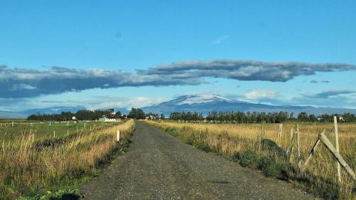 a dirt road in a field with a snow covered mountain at Guesthouse Spuni Cozy cottage 861 Hvolsvöllur in Hvolsvöllur