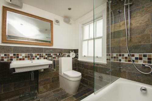 a bathroom with a sink and a toilet and a mirror at Sudeley House - by Brighton Holiday Lets in Brighton & Hove