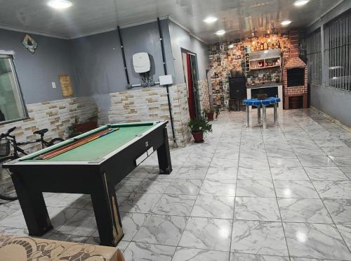un tavolo da biliardo in una grande stanza con un muro di mattoni di Quarto em casa de família a Belém