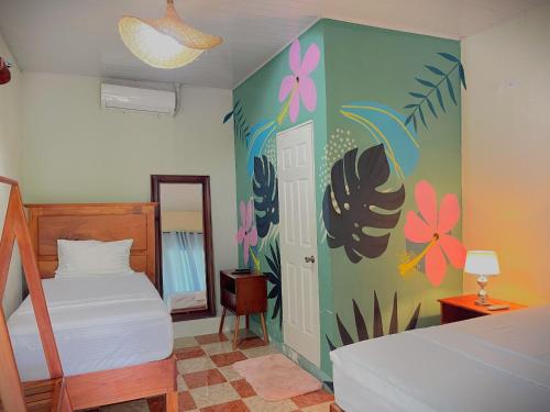 a bedroom with two beds and a mural of flowers at Hostal Edén in Moyogalpa