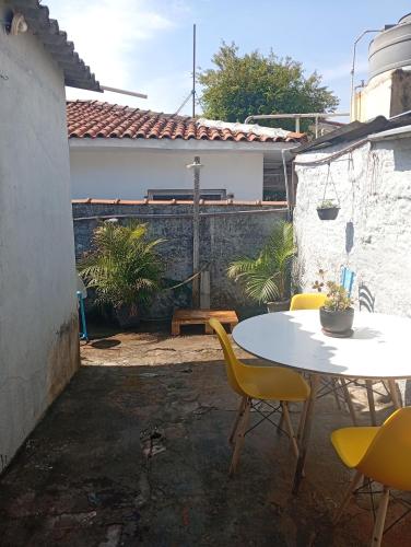 a patio with a white table and yellow chairs at O cafofo in Sao Paulo