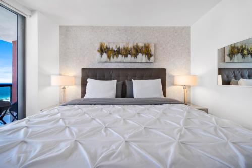 a bedroom with a large white bed with two lamps at BeachWalk Resort - VIP TOWER - OCEANVIEW UNIT 3 BEDROOM & 3 BATHROOM in Hallandale Beach