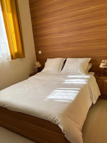 a bedroom with a large bed with a wooden headboard at Golden Sunset - Appart'Hôtel -Vue sur la ville in Antananarivo