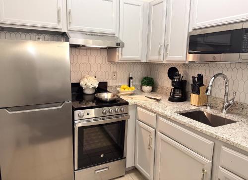 a kitchen with white cabinets and a stainless steel oven at Athens Hotel & Suites in Houston
