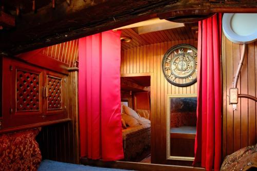 a bedroom with red curtains and a clock on the wall at The Victorian Voyager in Kemah