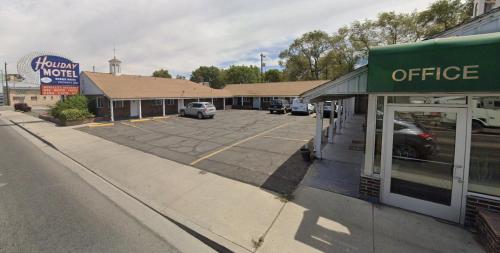 un estacionamiento con autos estacionados frente a una tienda en Holiday Motel, en Elko