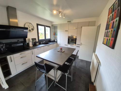 a kitchen with a table and chairs and a refrigerator at Maison familiale avec jardin - Proche Centre Pau in Gelos