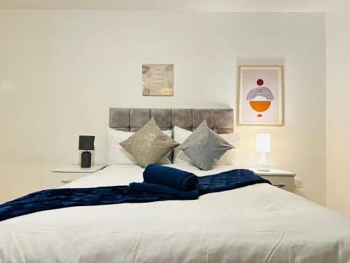 a white bed with a blue blanket on it at London NW Apartment in London