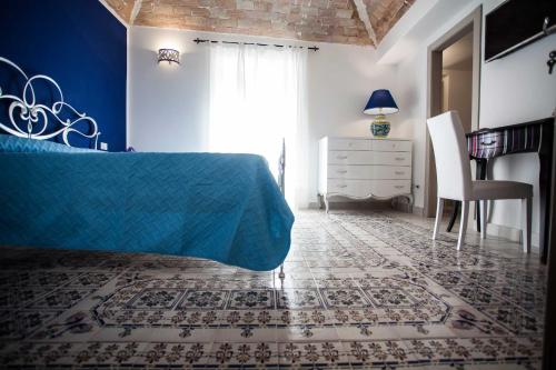 a bedroom with a blue bed and a desk and a chair at Palazzo Pagliaro in Santo Stefano di Camastra