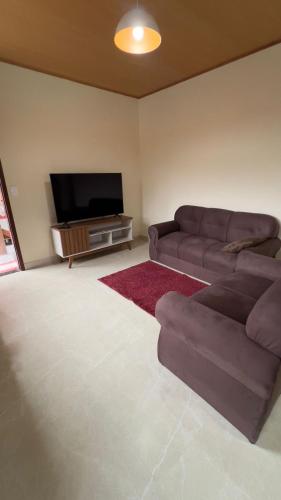 a living room with a couch and a flat screen tv at Casa Vale dos Peões Lumiar 3 in Nova Friburgo