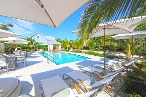 a swimming pool with chairs and umbrellas at Pomegranate Cottage in West Bay