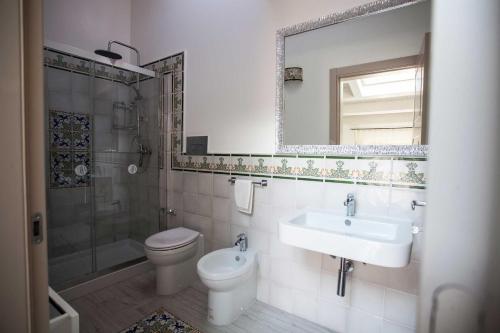 a bathroom with a sink and a toilet and a mirror at Palazzo Pagliaro in Santo Stefano di Camastra