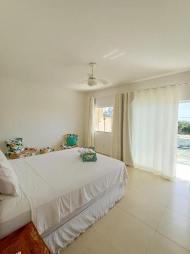 ein weißes Schlafzimmer mit einem Bett und einem Fenster in der Unterkunft Buzios casa porto da barra in Búzios