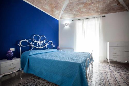 a blue bedroom with a bed and a blue wall at Palazzo Pagliaro in Santo Stefano di Camastra