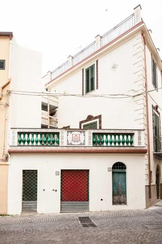 a white building with red doors on a street at Palazzo Pagliaro in Santo Stefano di Camastra