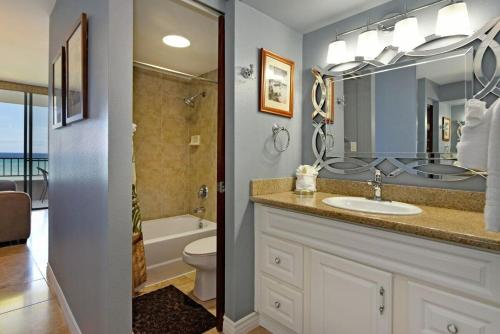 a bathroom with a sink and a toilet and a mirror at Paki Maui 207 · PM 207 BeachFront 1BD w Ocean View in Kahana