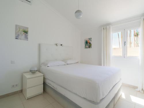 a white bedroom with a white bed and a window at FaroQuilla Suites Pasito Blanco in Pasito Blanco