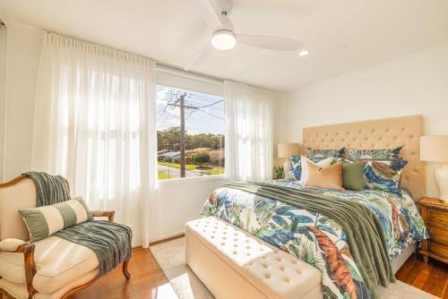 a bedroom with a bed and a window and a chair at Shoal Bay 83 , 83 Horace St - Air Conditioned home away from home in Shoal Bay