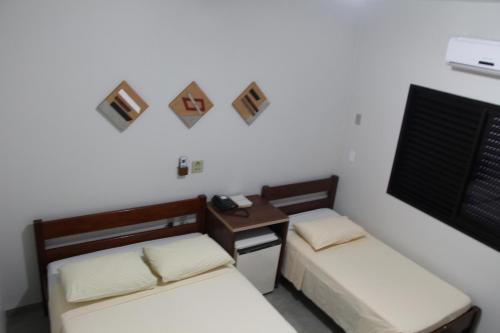 um quarto com 2 camas e uma secretária com um telefone em Paradise Hotel em Campo Grande