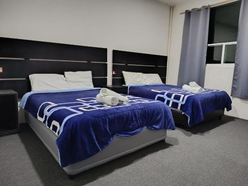 2 Betten in einem Zimmer mit blauer und weißer Bettwäsche in der Unterkunft Hotel Boutique Otomi cerca de Tolantongo in Cardonal