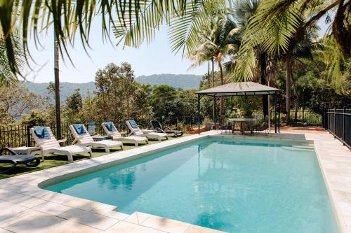 una piscina con sedie a sdraio e tavolo di Wybalena ocean views tropical big home garden pool a Port Douglas