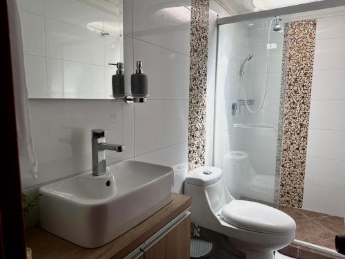 a white bathroom with a sink and a toilet at Kaobba Hostal in Medellín