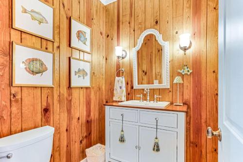 a bathroom with wooden walls and a sink and a mirror at Tenth Street Retreat in Tybee Island