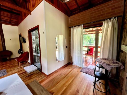 a living room with wooden floors and a large window at Chalés Aguas Serenas in Santo Antônio do Pinhal