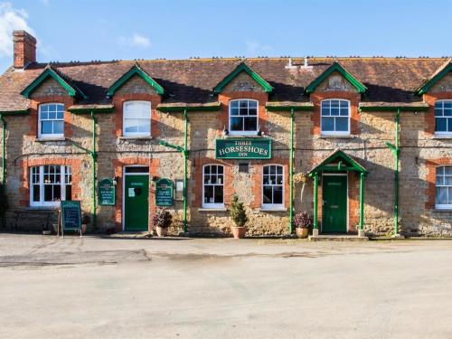 an old brick building with green doors and a sign at Three Horseshoes Inn in Powerstock