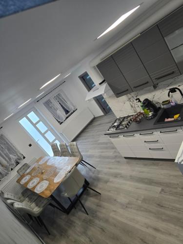 a kitchen with white cabinets and a wooden table at Casa Valy in Buşag