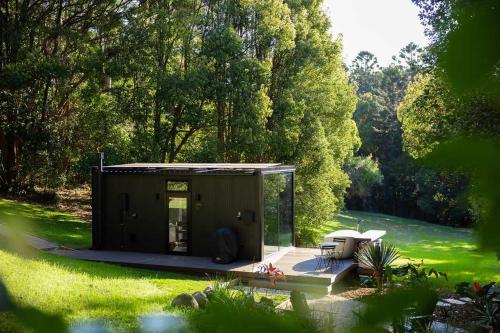a small shed in the middle of a garden at Luxury Mirror Home In Byron Bay in Byron Bay