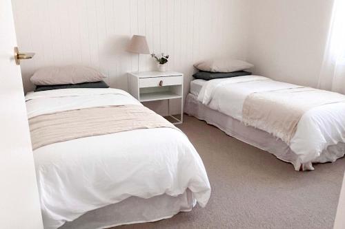 a bedroom with two beds and a table with a lamp at Luxury 3-Bed Family Retreat Office Kayaks & Yard in Marsden