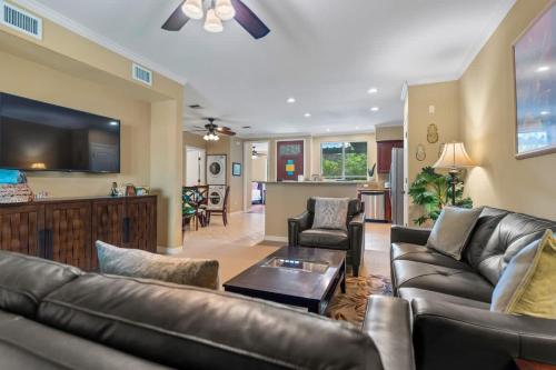 Il comprend un salon doté d'un mobilier en cuir et d'une télévision à écran plat. dans l'établissement Lovely Palm Villas Condo with Private Mauna Lani Beach Club Access, à Waikoloa
