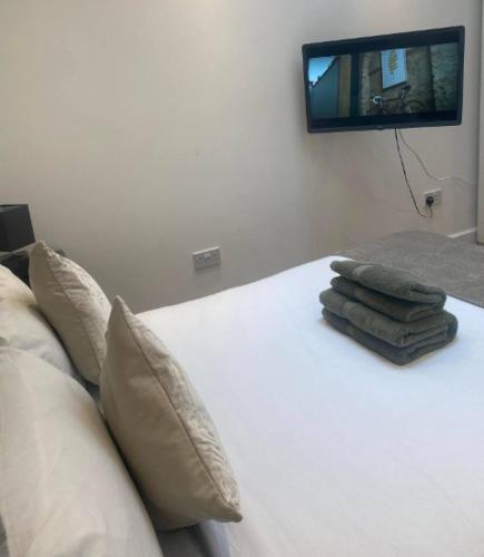 a bed with two pillows and a tv on the wall at Stunning Studio2, Banstead with free off st parking in Banstead