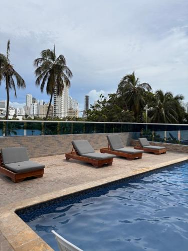 une rangée de chaises longues à côté d'une piscine dans l'établissement Fabuloso estudio con vista al laguito, à Carthagène des Indes