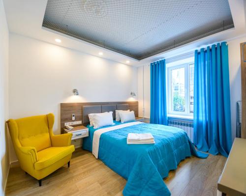 a bedroom with a blue bed and a yellow chair at Partner Guest House Baseina in Kyiv
